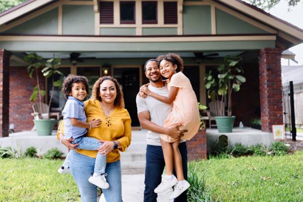 Portrait of multiracial parents holding their kids in front of the house